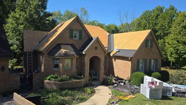 House with roofing being replaced; shingles removed, exposing wooden underlayment.